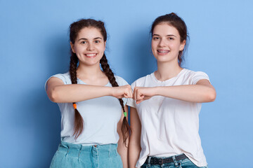 European young women give fist bump to each other, showing they friendly team, have positive...