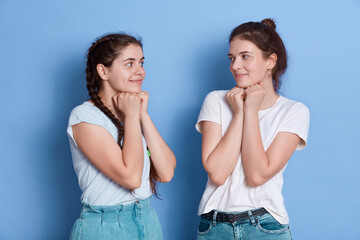 Two shy women friends european girls in casual clothes posing isolated over blue wall, ladies...