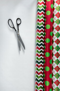 3 rolls of colorful paper and scissors are ready for wrapping Christmas presents