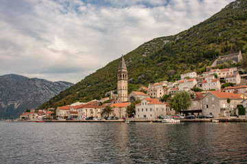 Fototapeta na wymiar Perast historic town at Kotor bay. Ancient city in Montenegro. Beautiful bay with old buildings, cafes, restaurants and parked tourist cars.