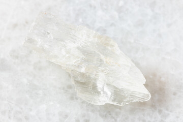 closeup of sample of natural mineral from geological collection - rough Petalite rock on white marble background from Araguai, Brazil