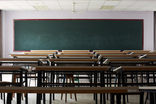 Empty classroom with rows of student tables and blackboard