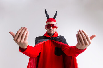 Strange devilish man in sunglasses and black red halloween costume posing over white background.