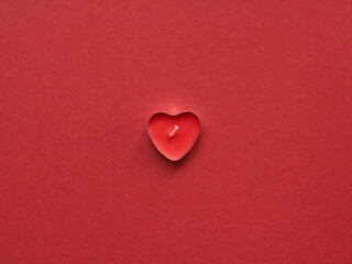Hearth shaped candle on red background. love background
