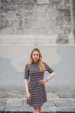 Serious Young Woman Posing in front of an Old Plaster Wall in It