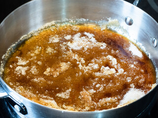 cooking salted butter caramel sauce at home kitchen - heating and melting sugar in steel pan close up