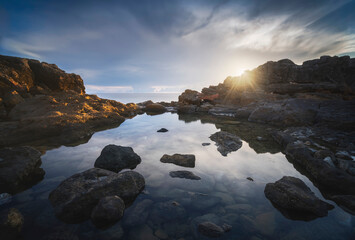 Sunset behind the rocks and sea pool in Castiglioncello coast. Tuscany, Italy.