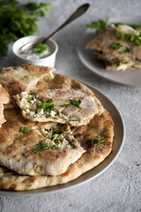 Khachapuri with cottage cheese and sour cream with green parsley on the plate. Top view