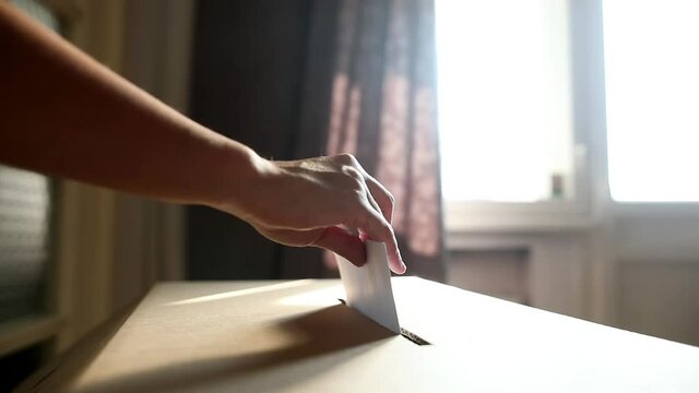 Conceptual footage of a person voting, casting a ballot at a polling station, during elections.