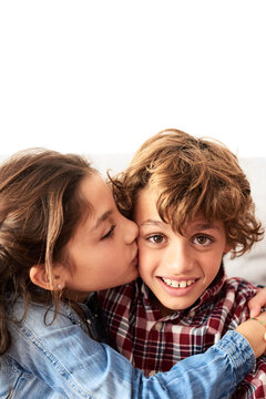 Sister kissing her brother in cheek.
