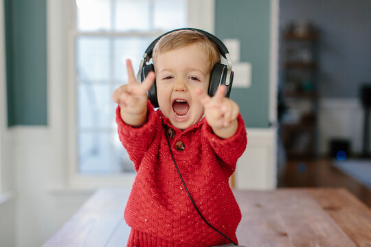 Cute young boy sitting on a table listening to music headphones