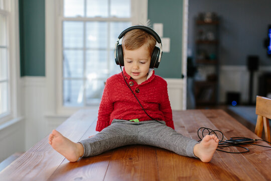 Cute young boy sitting on a table listening to music headphones
