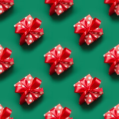 Seamless pattern of gifts in red and white packaging with polka dots and red bow on green...