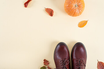 Trendy leather shoes on yellow background with autumn leves and pumpkin. Fall Fashion casual Look. Autumn Minimal Design. Flat lay, copy space