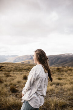 young woman standing looking away in mountain landscape