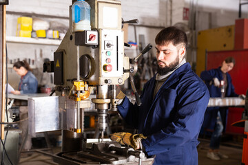 Fototapeta na wymiar Portrait of confident man mechanic using drilling machine in workshop