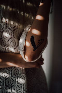 Close up of a woman in lace shirt with tattoed hand