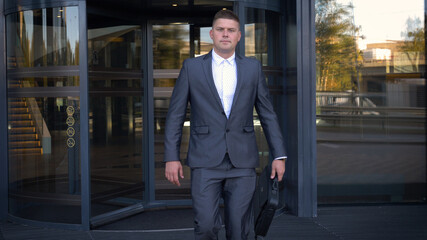 Businessman in a fromal suit in a business center enter the building with briefcase.