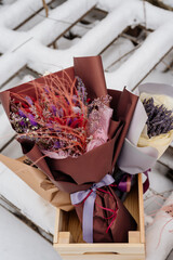 Bouquet of dried flowers in package on background of small bouquets of dried plants in box