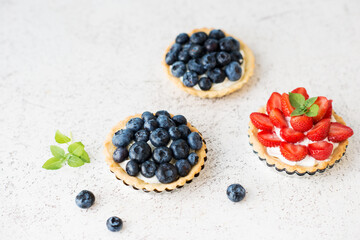 Sweet tarts with fresh summer berries, raspberries, strawberries and blueberries, selective focus