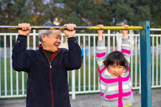Senior Man teach his Granddaughter use parallel bars outdoor