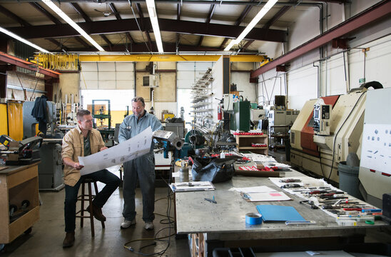 Factory workers discussing blue prints