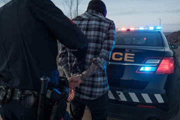 A Police Officer handcuffs a tattooed suspect.
