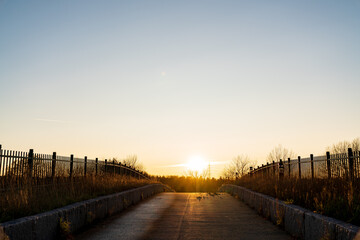 Paved road, with the sun rising behind the bridge first thing in the morning.