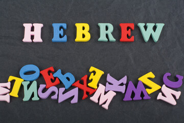 HEBREW word on black board background composed from colorful abc alphabet block wooden letters, copy space for ad text. Learning english concept.