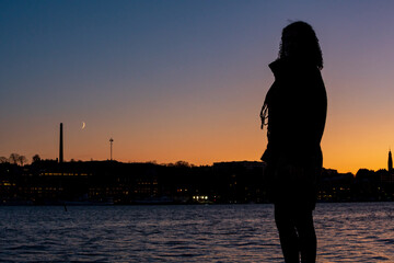 Young woman watching the sunset and the moon rising