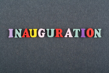 Iinauguration . English word on black board background composed from colorful abc alphabet block wooden letters, copy space for ad text. Learning english concept.