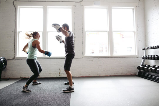 Strong, healthy woman working out in gym - boxing with trainer