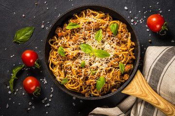 Pasta Bolognese in the skillet at black table.