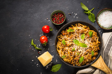 Pasta Bolognese in the skillet at black table.