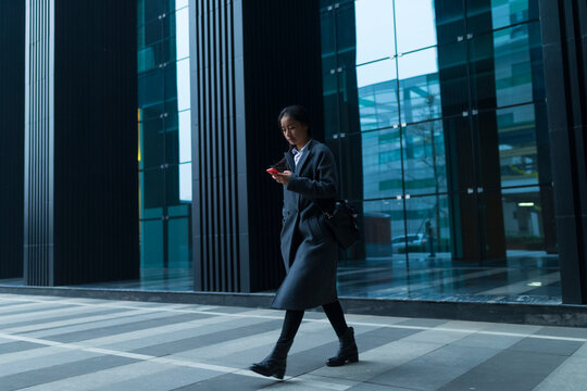 One Young Asian Business Woman Walking in the Evening Street
