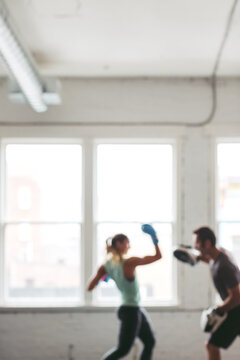 Strong, healthy woman working out in gym - boxing with trainer