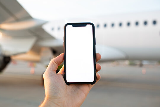 Mockup image of modern cell phone. Man Hand holding blank desktop screen mobile phone airport and airplane in the background. Travel concept remote work video call