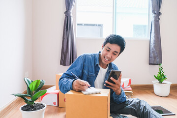 Asian man writing order product from customer calls to order he notes on notepad To prepare cargo or goods To transport to customers On days with new normol covid-19