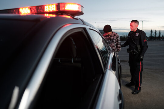 A Police Officer holds the arm of a detained suspect