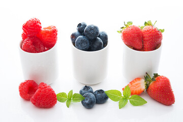 Fresh summer berries in glasses on a white background, strawberries, raspberries, blueberries, close-up