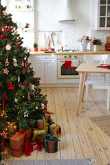 Interior of a new year's kitchen decorated with festive decor and a Christmas tree in a cozy bright house