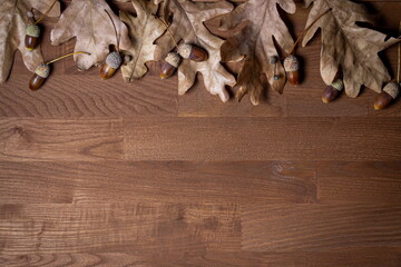 Autumn background for an inscription. Autumn leaves and acorns on a wooden surface. Dry oak leaves