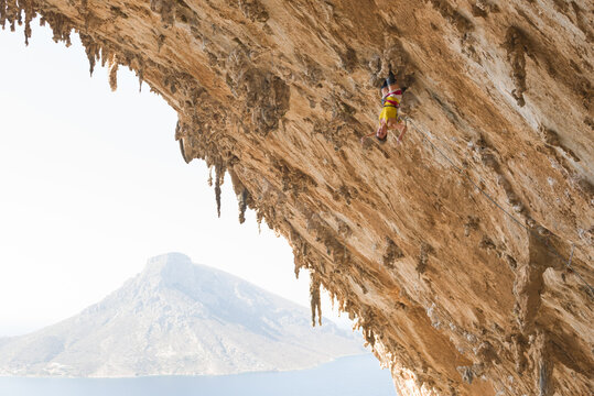 Female rock climber hanging on craggy wall in Kalymnos, Greece