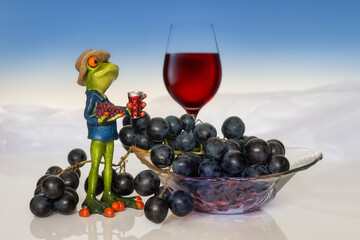 Dark grapes, a vintner frog and a glass of red wine