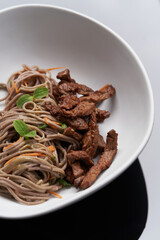 Thai soba salad in white bowl. Stir fry noodles, Soba salad with vegetables and meat.