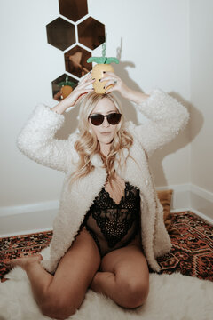Fashionable woman in fur jacket and lingerie with pineapple sippy cup, New Years Party.