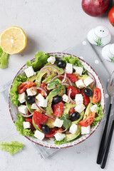 Healthy salad with avocado, tomatoes, feta, black olives and red onion on grey background, healthy eating day, Top view
