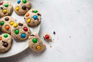 Chocolate chip american cookies and colored sweets on a plate on a gray background. For calendar, cookbook, recipes, cards.