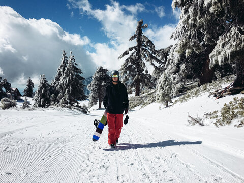 Male Snowboarder Hiking Snowy Trail with Board