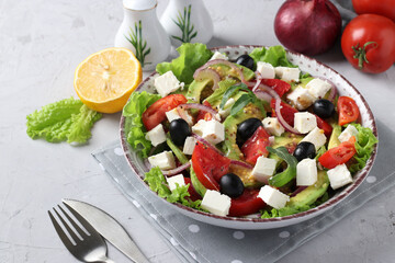 Healthy salad with avocado, tomatoes, feta, black olives and red onion on grey background, healthy eating day, Closeup